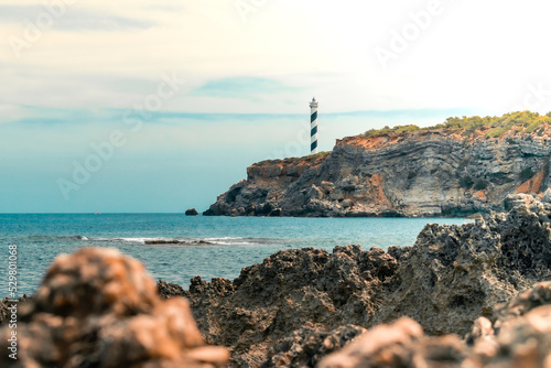 Amanecer en Faro de Portinatx en Ibiza desde las rocas que se adentran en el mar photo