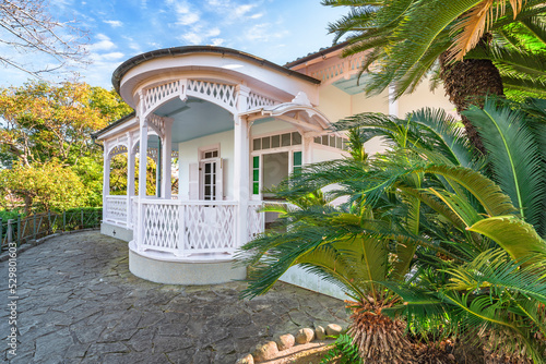 nagasaki, kyushu - december 13 2021: Entrance of the former residence of the president of the Nagasaki district court established in 1883 in the Glover Garden with fretwork arches and palm trees.
