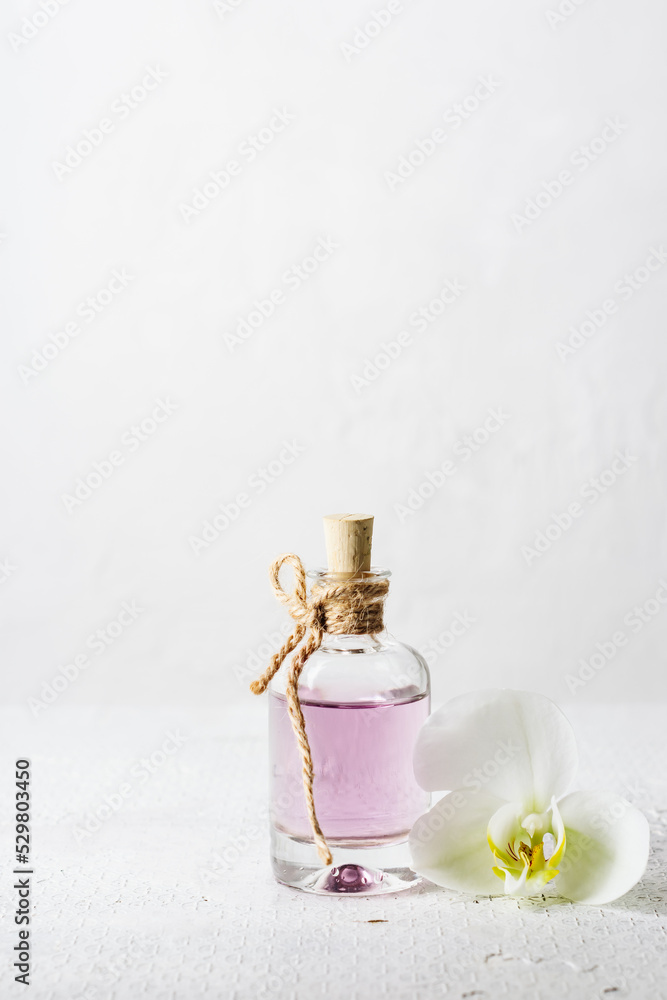 Rose essential oil in glass bottle and orchid flower.
