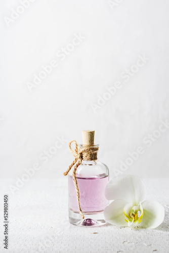 Rose essential oil in glass bottle and orchid flower.