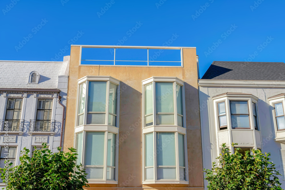 Three adjacent homes with bay windows against the clear sky at San Francisco, California