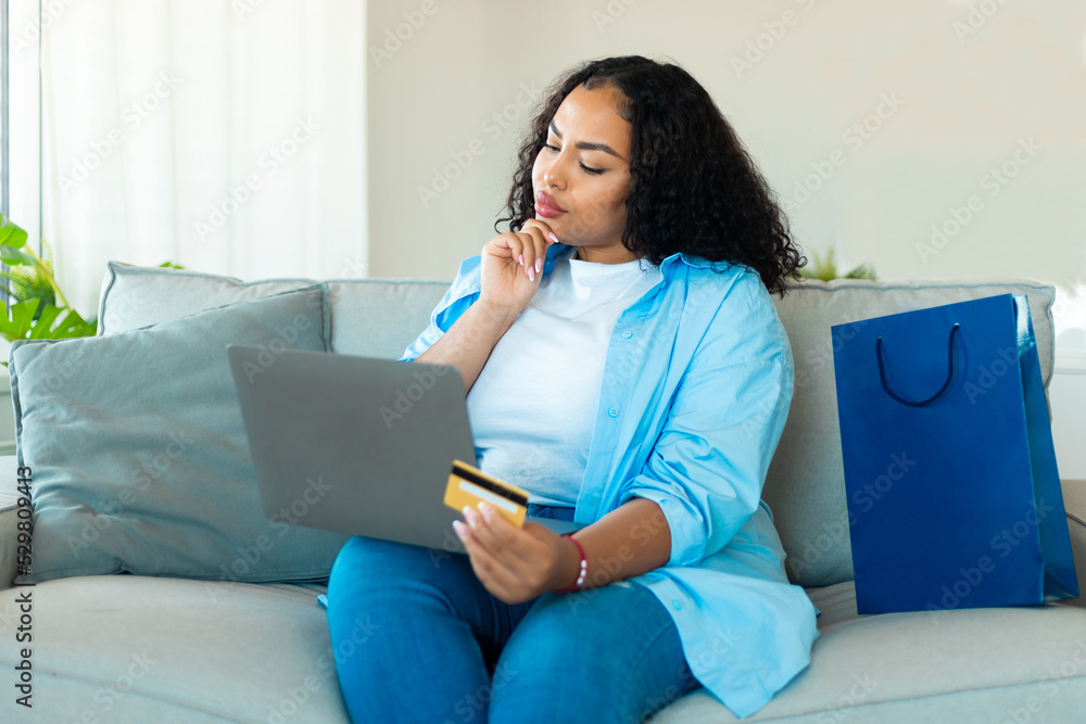 Thoughtful African Lady Shopping Via Laptop And Credit Card Indoor