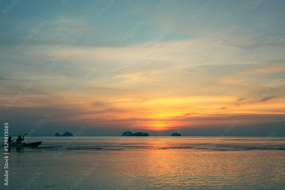 Silhouettes of a couple kayaking in the sea at sunset