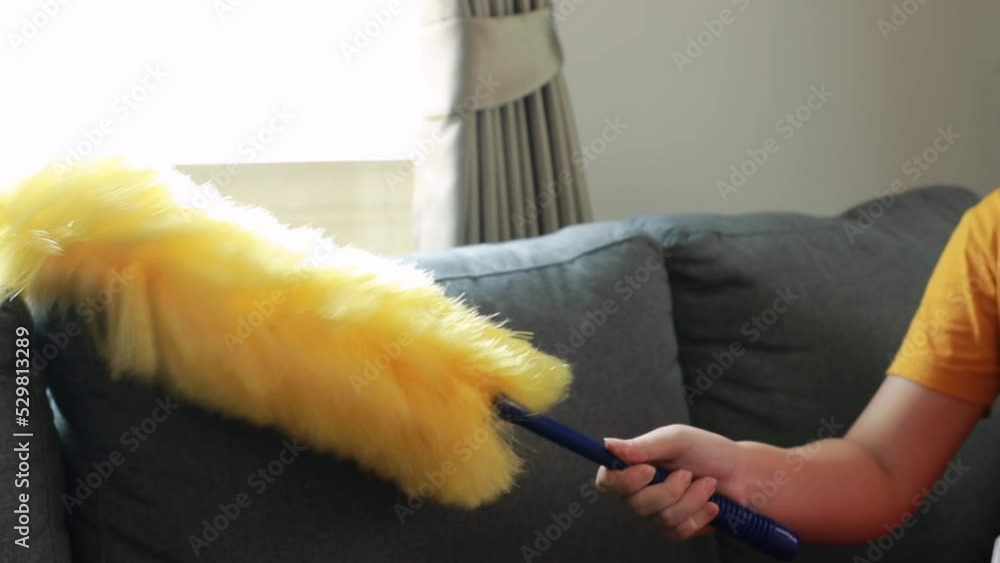 Asian woman who does housework without mask uses duster to dust the
