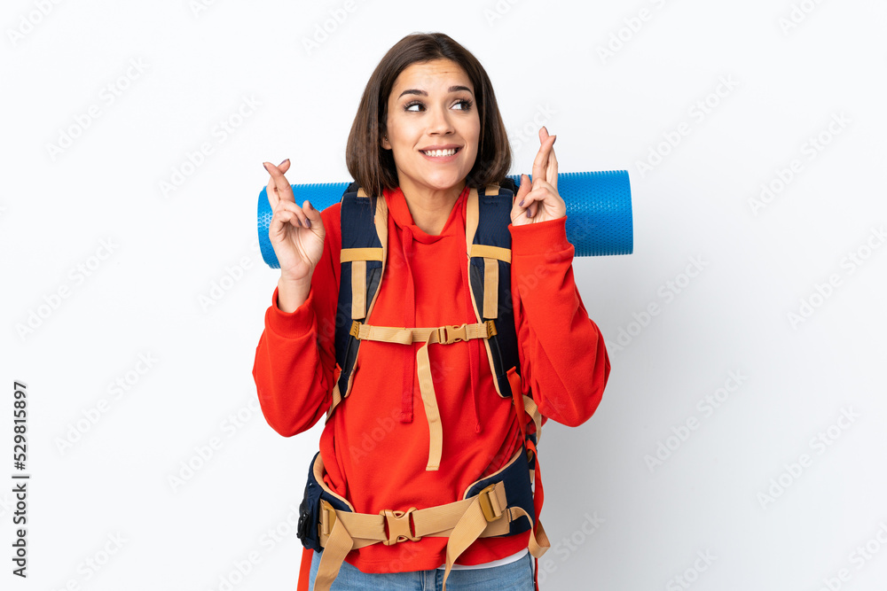 Young caucasian mountaineer girl with a big backpack isolated on white background with fingers crossing Young caucasian mountaineer girl with a big backpack isolated on white background with fingers crossing