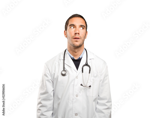 Astonished doctor looking against white background
