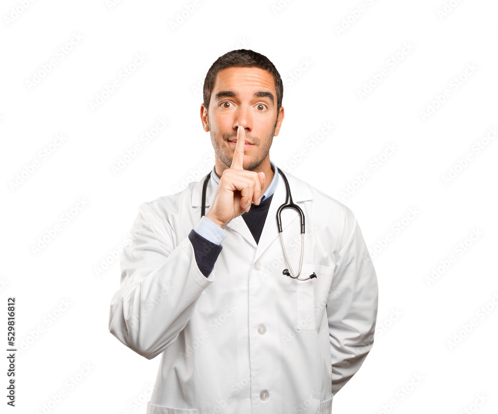 Serious doctor with silence gesture against white background Serious doctor with silence gesture against white background