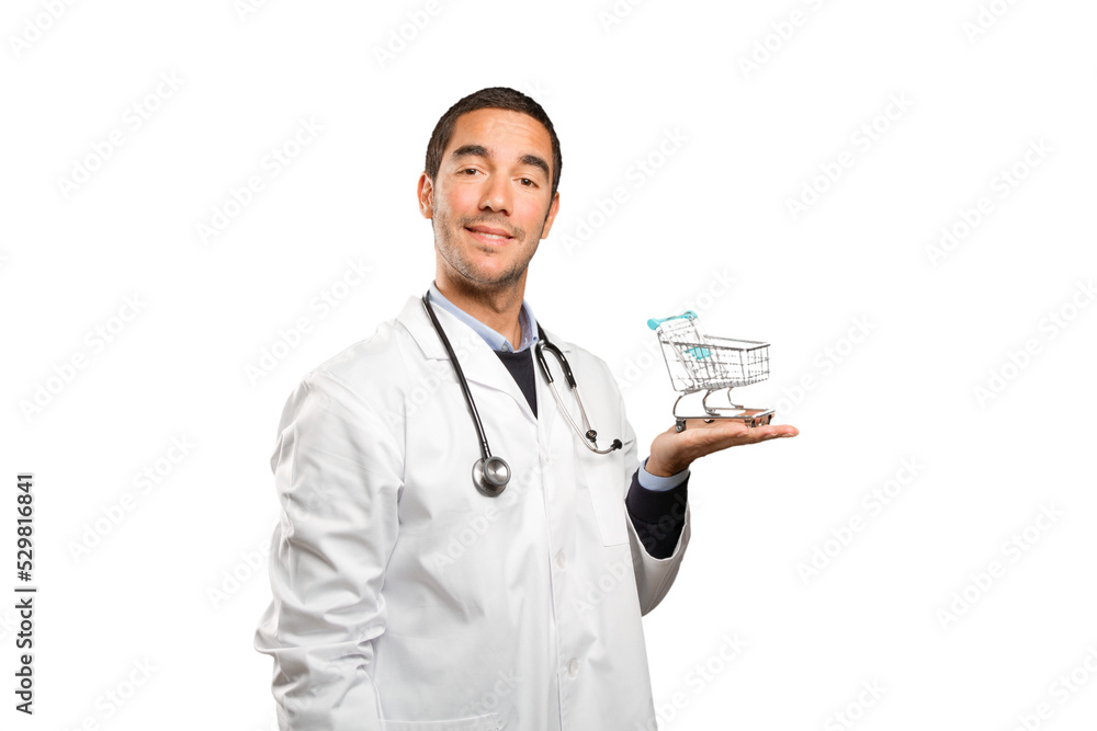 Satisfied doctor holding a shopping cart against white background Satisfied doctor holding a shopping cart against white background
