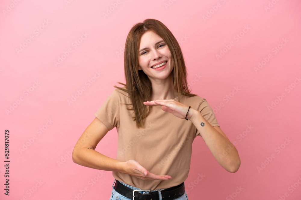 Young English woman isolated on pink background holding copyspace imaginary on the palm to insert an ad Young English woman isolated on pink background holding copyspace imaginary on the palm to insert an ad
