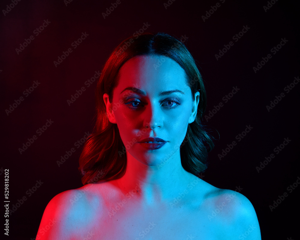 Close up portrait of beautiful woman model, with pink and blue neon lighting in studio with dark background.
Close up portrait of beautiful woman model, with pink and blue neon lighting in studio with dark background.