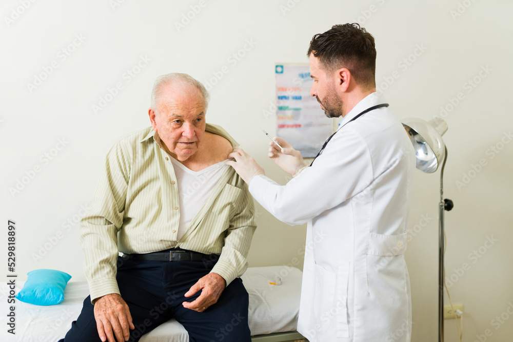 Fototapeta premium Doctor giving a shot or medical treatment to a elderly sick man