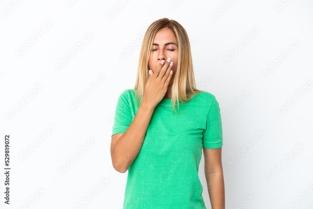 Blonde Uruguayan girl isolated on white background yawning and covering wide open mouth with hand Blonde Uruguayan girl isolated on white background yawning and covering wide open mouth with hand