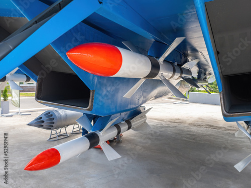 Aerial unguided missiles. Air bombs under aircraft. Avia armament. Military technologies. Air rockets on blue plane. Non-guided bombs are fixed under wing. Fighter fragment. Air force photo