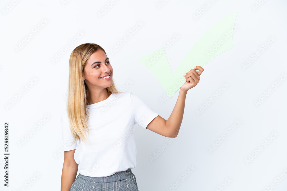 Blonde Uruguayan girl isolated on white background holding a check icon with happy expression