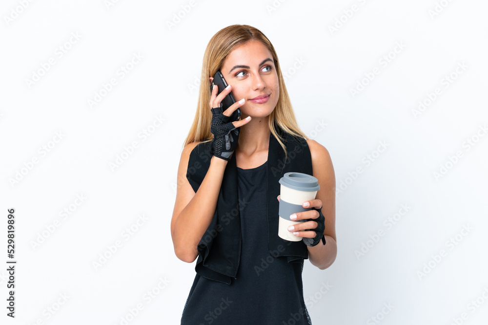 Blonde Uruguayan sport girl isolated on white background holding coffee to take away and a mobile Blonde Uruguayan sport girl isolated on white background holding coffee to take away and a mobile