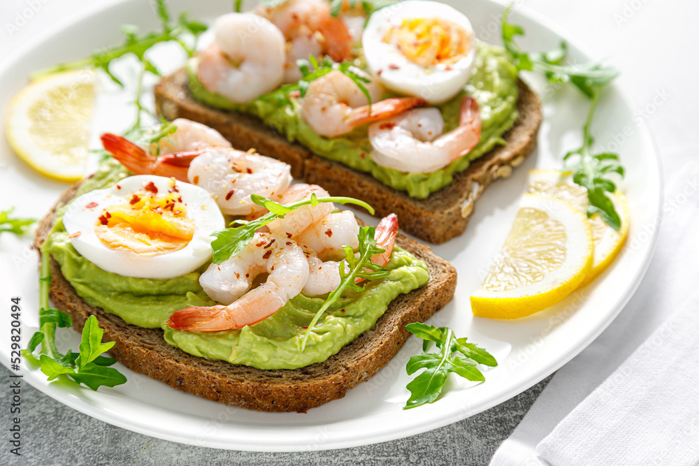 Toast with shrimps, avocado guacamole, arugula and boiled egg