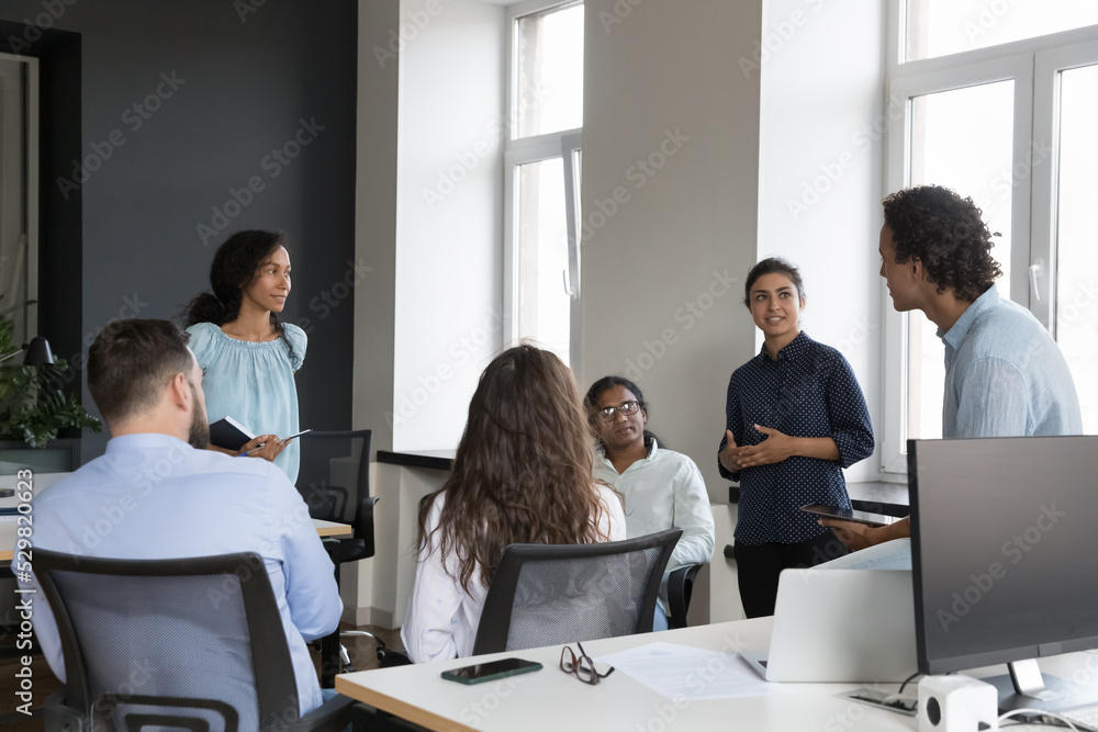 Young multiethnic business team brainstorming in office, discussing project, negotiating on work process. Corporate group sitting in circle, talking, sharing ideas on meeting