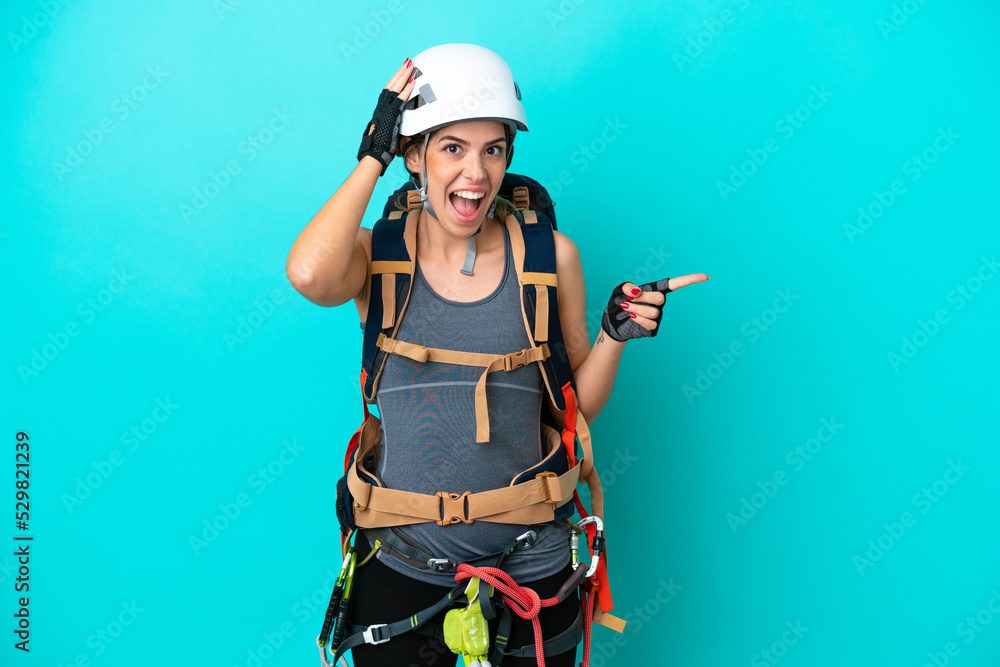 Young Italian rock-climber woman isolated on blue background surprised and pointing finger to the side