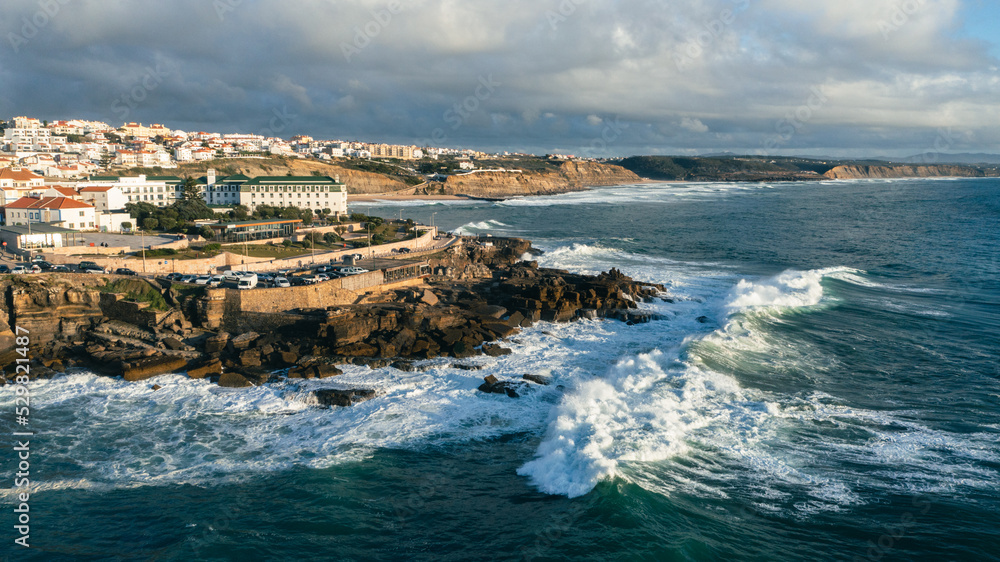 Aerial view of a beautiful tourist town located on the shore of the Atlantic Ocean.  Panorama of the city from a drone with a  rocky ocean coastline during sunset. Scenic nature landscape  from drone