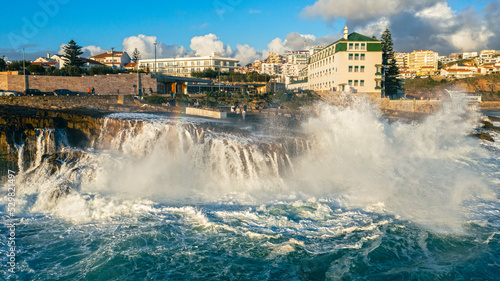 People look at the big waves crashing on the pier. Tourists contemplate the splashes of waves crashing on the rocky shore during sunset. People n stand and looking on the ocean. Freedom and travel