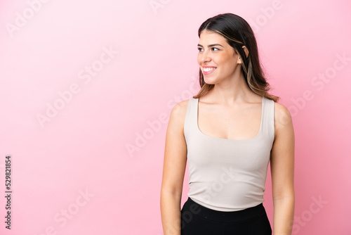 Young Italian woman isolated on pink background looking side