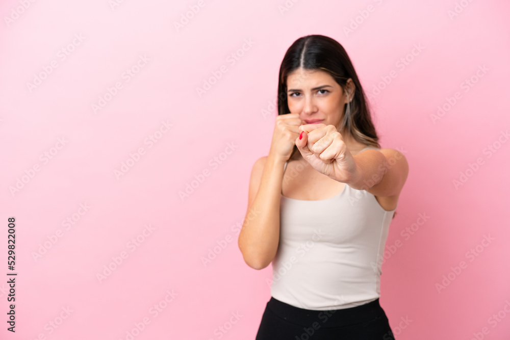 Young Italian woman isolated on pink background with fighting gesture Young Italian woman isolated on pink background with fighting gesture