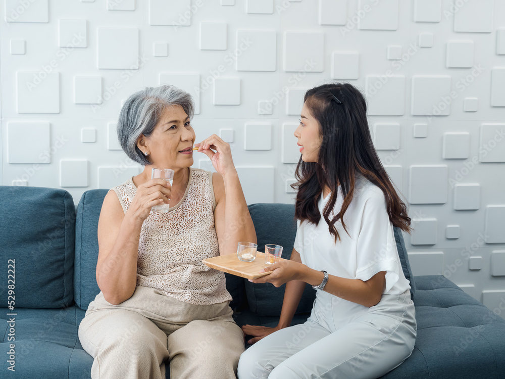 Portrait of Asian senior woman grey short hair holds pill and a glass of drinking water from young adult daughter, taken daily medicine or vitamin supplements, elderly healthcare and medical at home. Portrait of Asian senior woman grey short hair holds pill and a glass of drinking water from young adult daughter, taken daily medicine or vitamin supplements, elderly healthcare and medical at home.