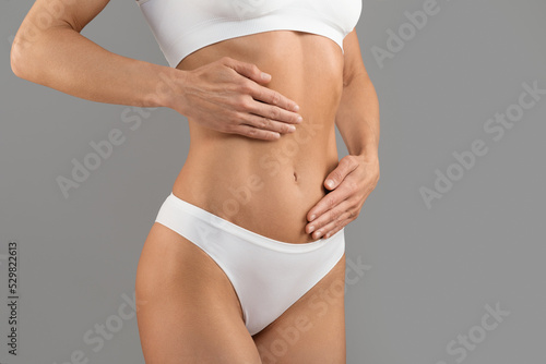Cropped Of Young Female In White Underwear Touching Belly With Two Hands © Prostock-studio