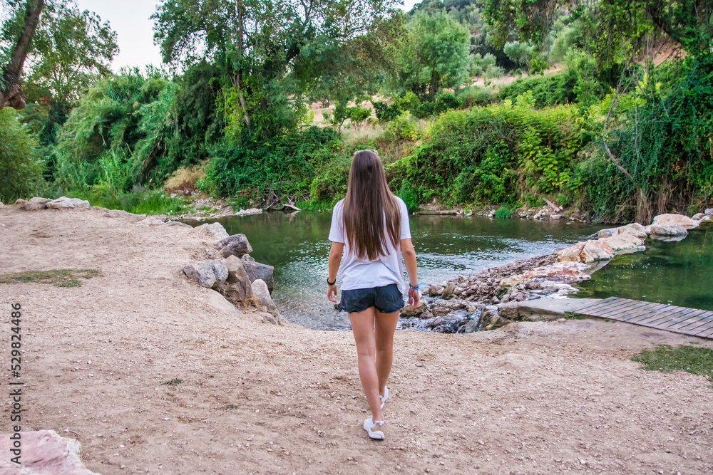 Rear view of a young Caucasian woman walking towards a river in the middle of nature. Nomadic lifestyle. Image with copy space