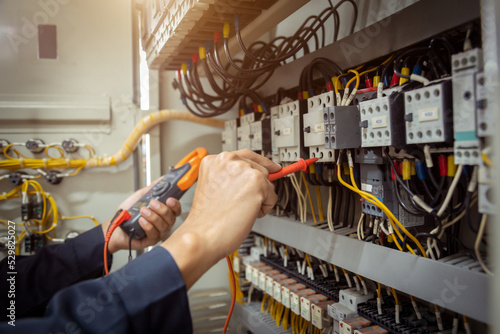 Obraz na plátně Electrical engineer using measuring equipment to checking electric current voltage at circuit breaker and cable wiring system , Electrical service concept