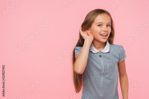 Closeup cropped small caucasian preteen teenage girl schoolgirl in blue dress overhearing eavesdrop gossips rumors secrets news isolated in pink background