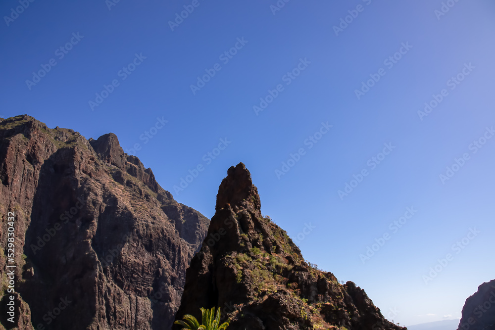 Sharp pinnacle in centre of remote tourist village Masca in the Teno mountain range, Tenerife, Canary islands, Spain, Europe. Rock formation is surrounded by steep cliffs. Gulch connceted to the sea