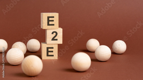 wooden cubes block with text e2e, brown background photo