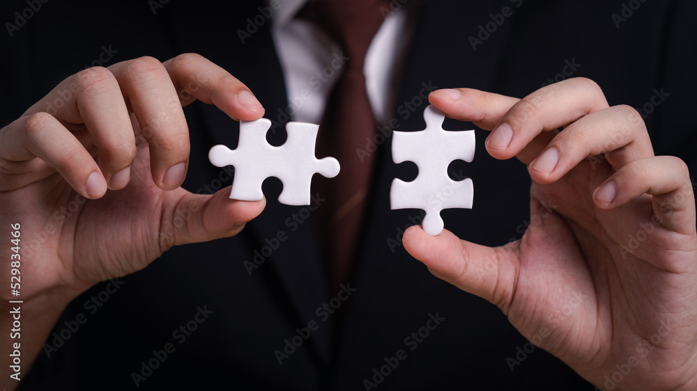 Businessman hand holding jigsaw puzzle trying to connect couple puzzle piece. Solution and solve Jigsaw puzzle. one part of whole. symbol of association and connection. business strategy. Businessman hand holding jigsaw puzzle trying to connect couple puzzle piece. Solution and solve Jigsaw puzzle. one part of whole. symbol of association and connection. business strategy.