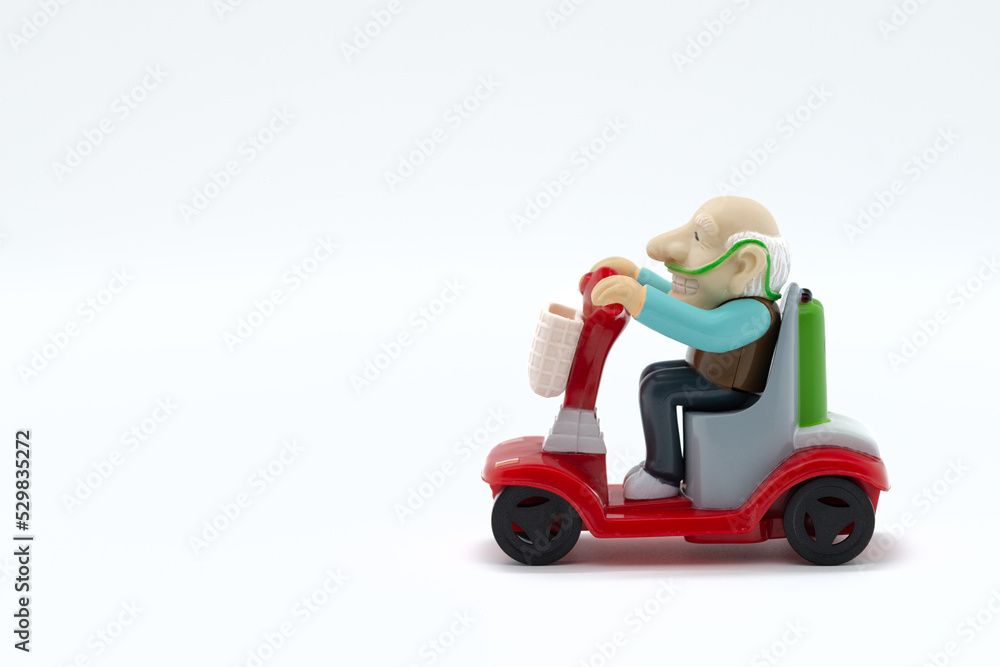 Grandfather on motorized wheelchair, toys, white background, cropped image