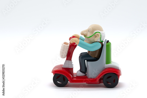 Grandfather on motorized wheelchair, toys, white background, cropped image photo