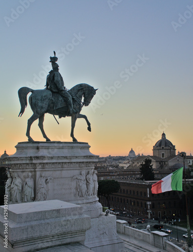 Sunset at Piazza Venezia. View of the statue of Victor Emmanuel II, the Italian flag, the skyline of Rome: beautiful domes, basilicas, cathedrals