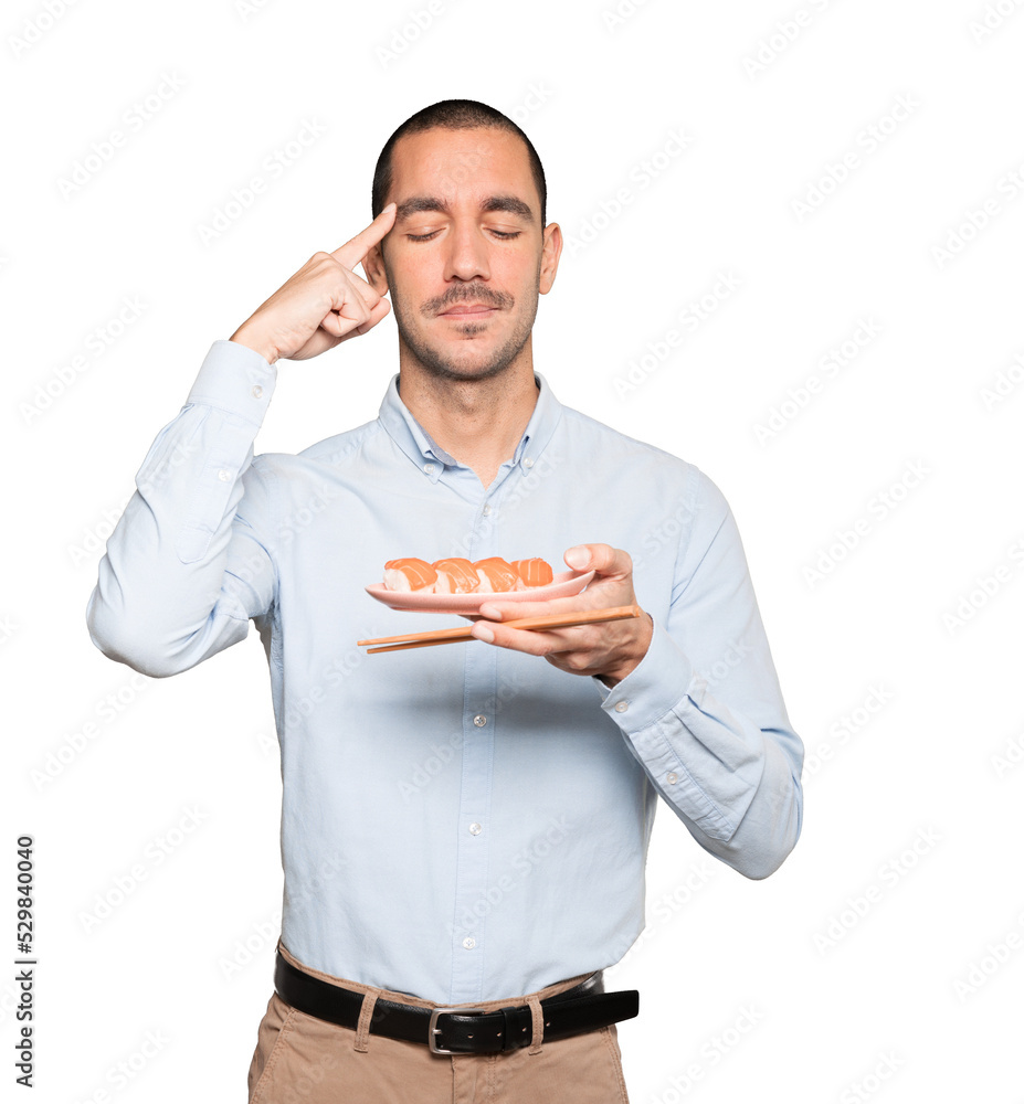 Young man using chopsticks to eat sushi Young man using chopsticks to eat sushi