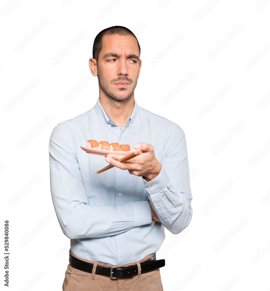 Young man using chopsticks to eat sushi Young man using chopsticks to eat sushi