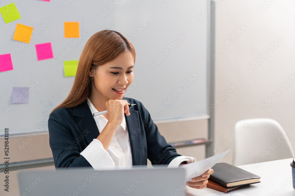 Concept of modern girl leadership, Businesswoman read financial document while holding pen to chin Concept of modern girl leadership, Businesswoman read financial document while holding pen to chin