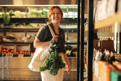 Happy young woman grocery shopping in a supermarket