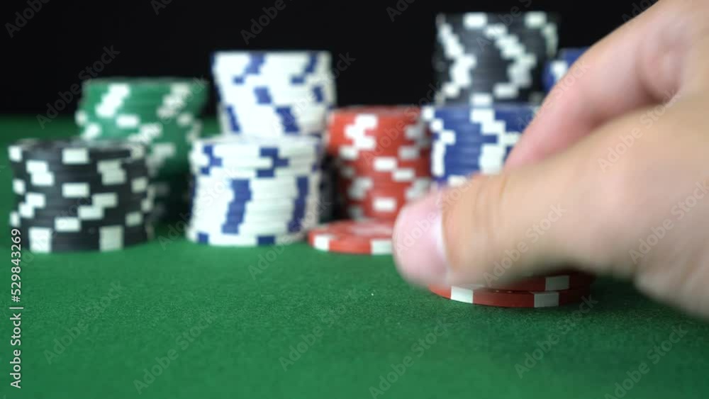 Male hand sorting through a stack of red poker chips. Chips fall on each other back to the turret