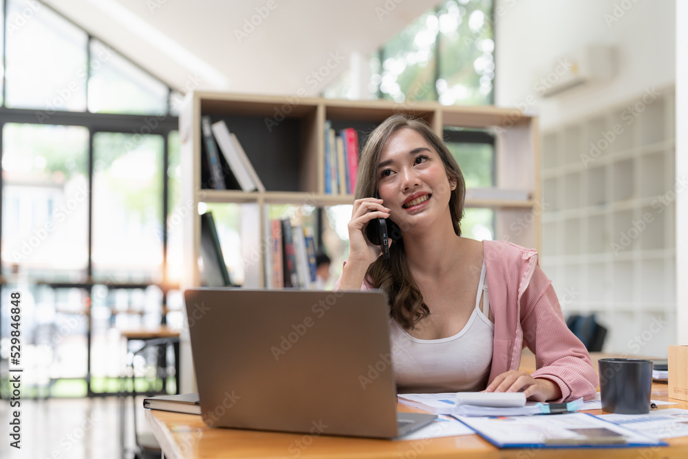 Attractive young female having smartphone conversation in modern library. Financial accounting concept. Attractive young female having smartphone conversation in modern library. Financial accounting concept.
