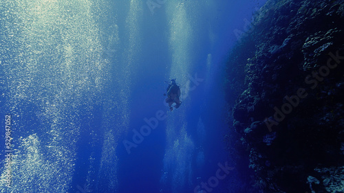 Underwater photo of scuba diver at a drop off coral wall