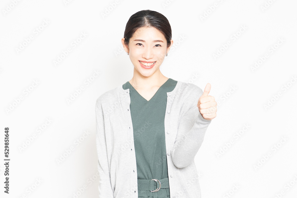 白背景の前で、良いねのポーズをする女性 白背景の前で、良いねのポーズをする女性