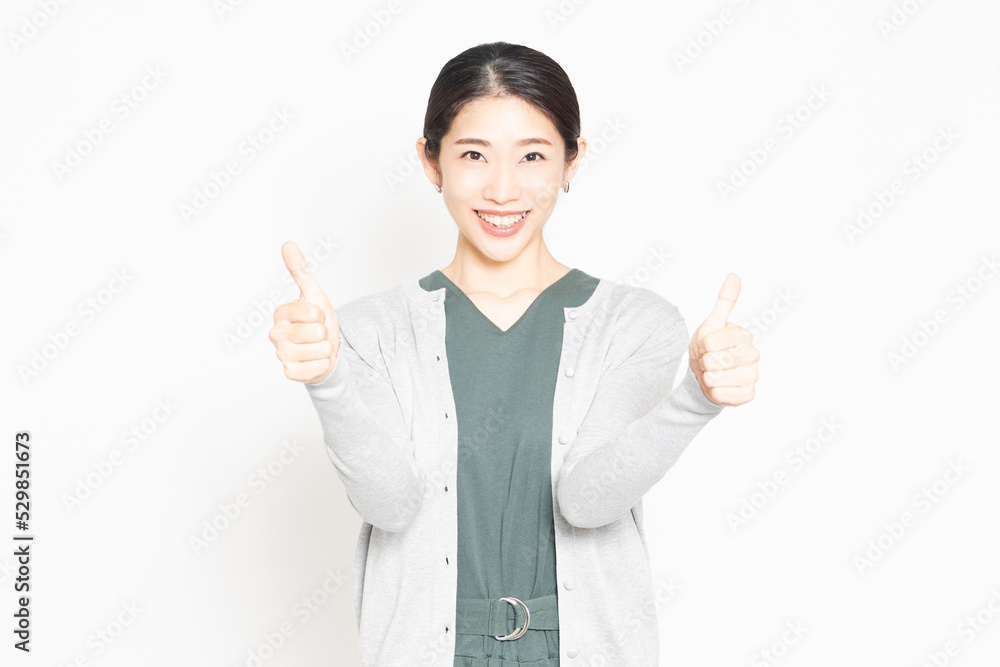 白背景の前で、良いねのポーズをする女性 白背景の前で、良いねのポーズをする女性