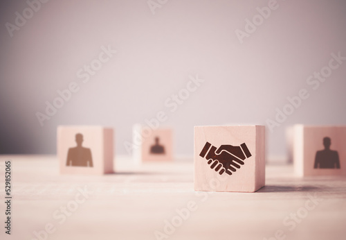 Handshaking icon which prints screen on wood cube block with the human icon for teamwork, brainstorming, cooperation business deal and agreement, and business success concept