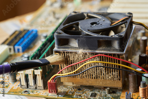 Brush cleaning an old computer board from dust and dirt. Close-up.