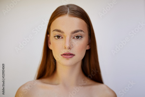 Beauty PhotoshootBeauty photoshoot.  Female model with red hair, brown eyes, freckles, clear skin, against a white backdrop.