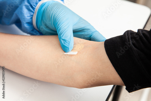 Nurse putting a Band-Aid on a patient s arm after taking a blood sample